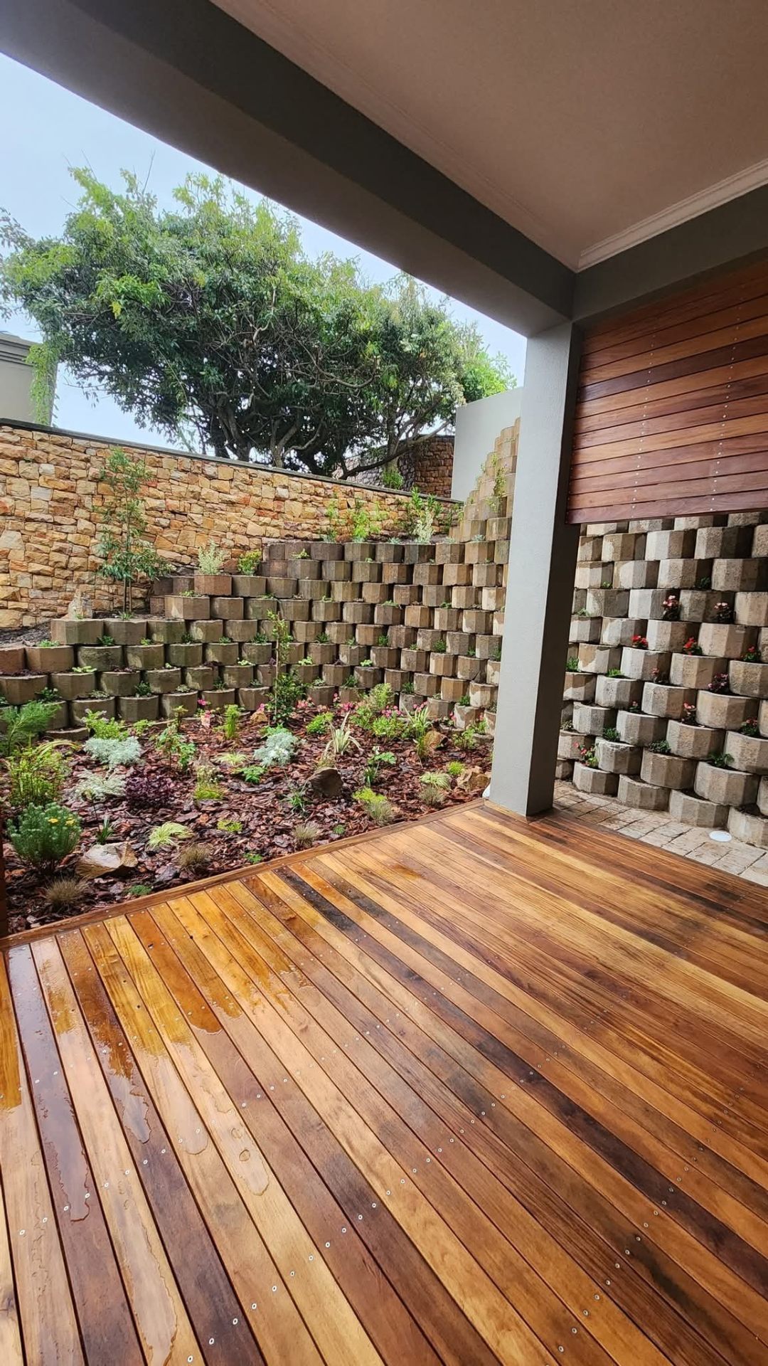 Hardwood deck with stacked stone retaining walls and landscaped garden