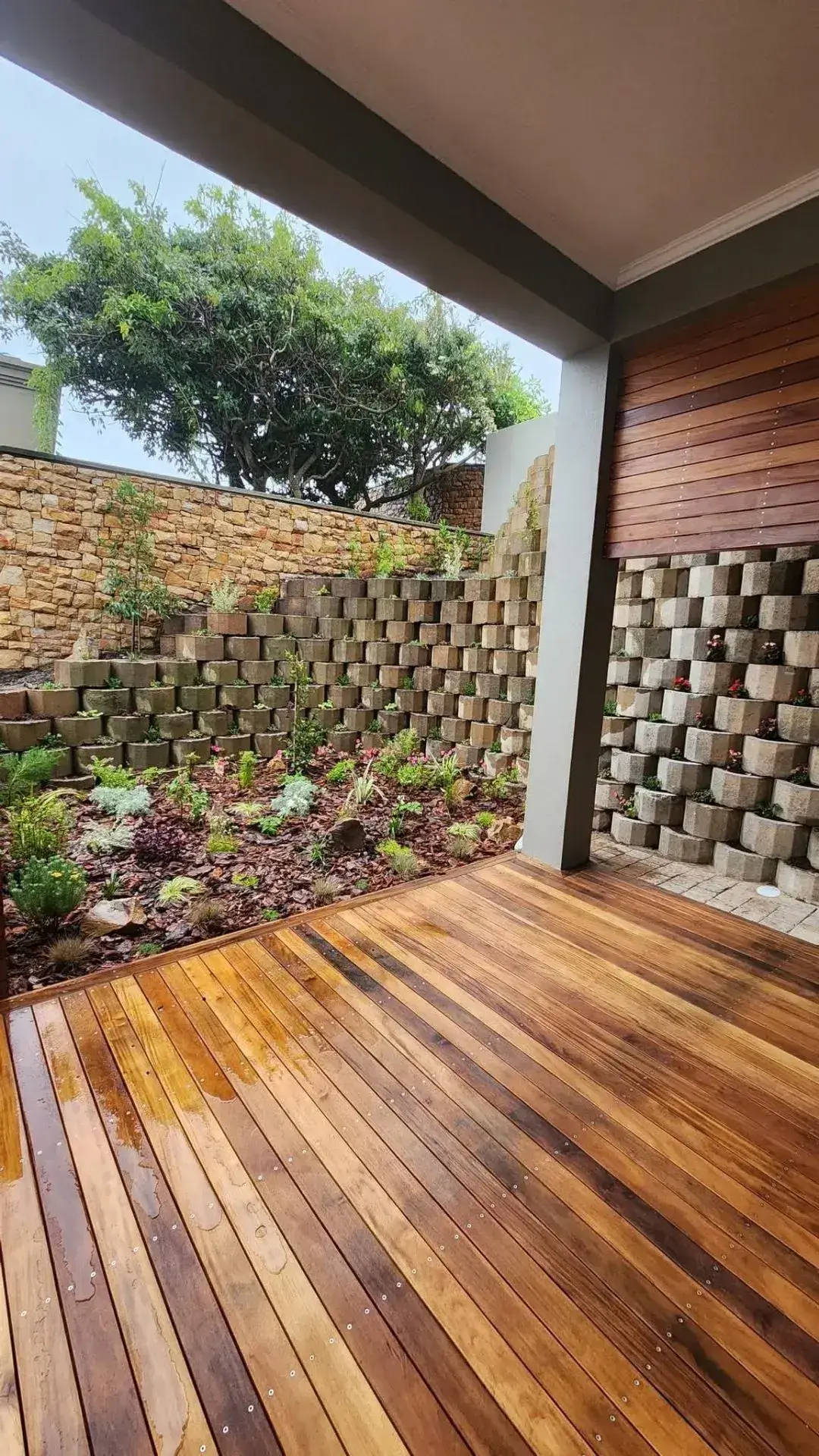 Hardwood deck with stacked stone retaining walls and landscaped garden