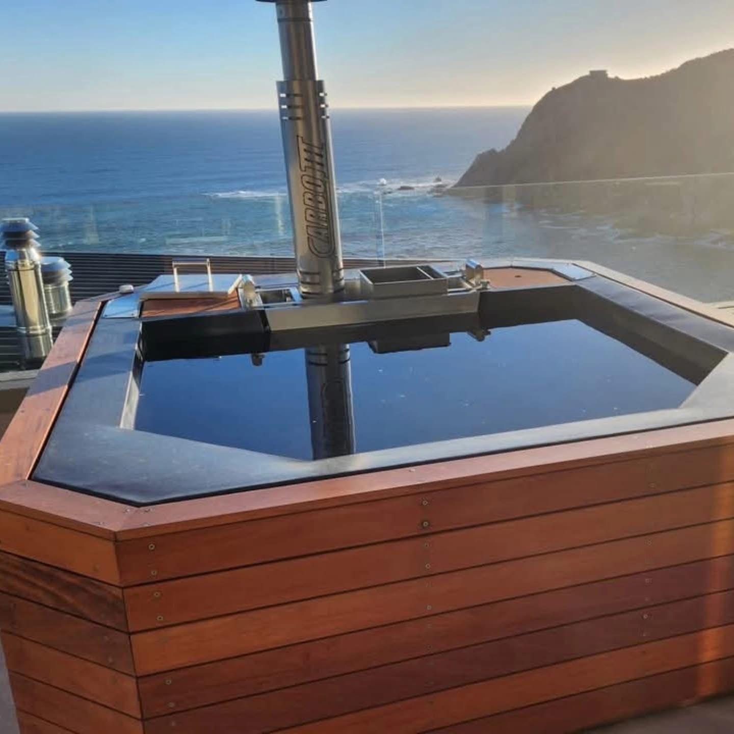 Custom timber-clad wood-fired hot tub with panoramic ocean views