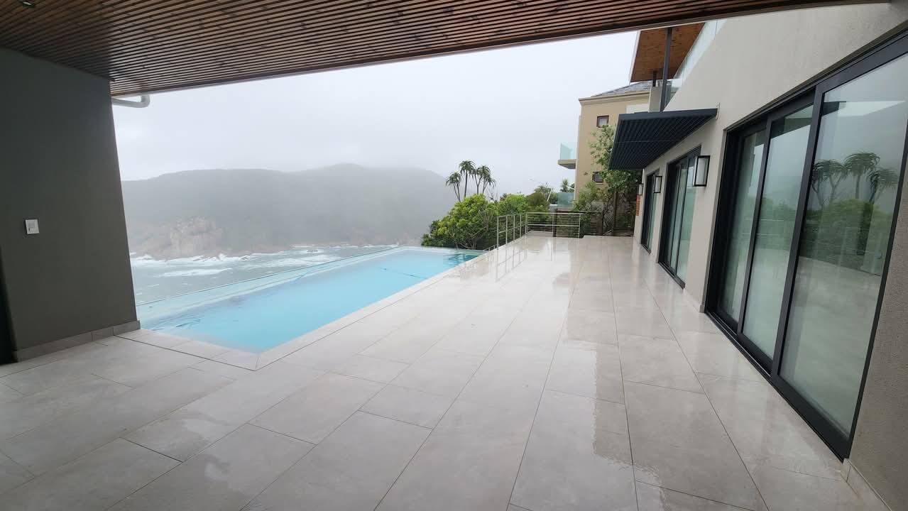 Infinity pool and tiled deck with ocean and mountain views