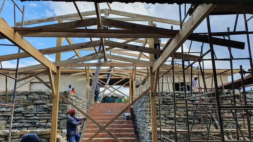 Timber roof trusses being installed over stone-clad walls