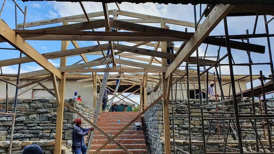 Timber roof trusses being installed over stone-clad walls